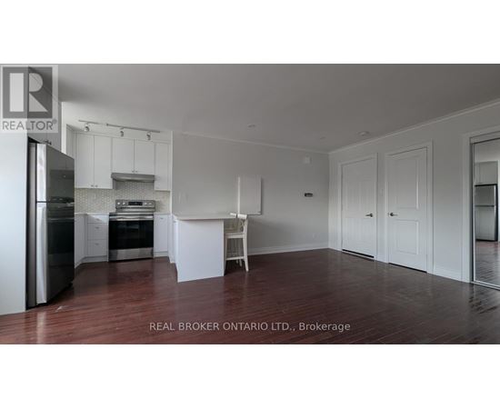 A white kitchen with a refrigerator, sink, and cabinets.