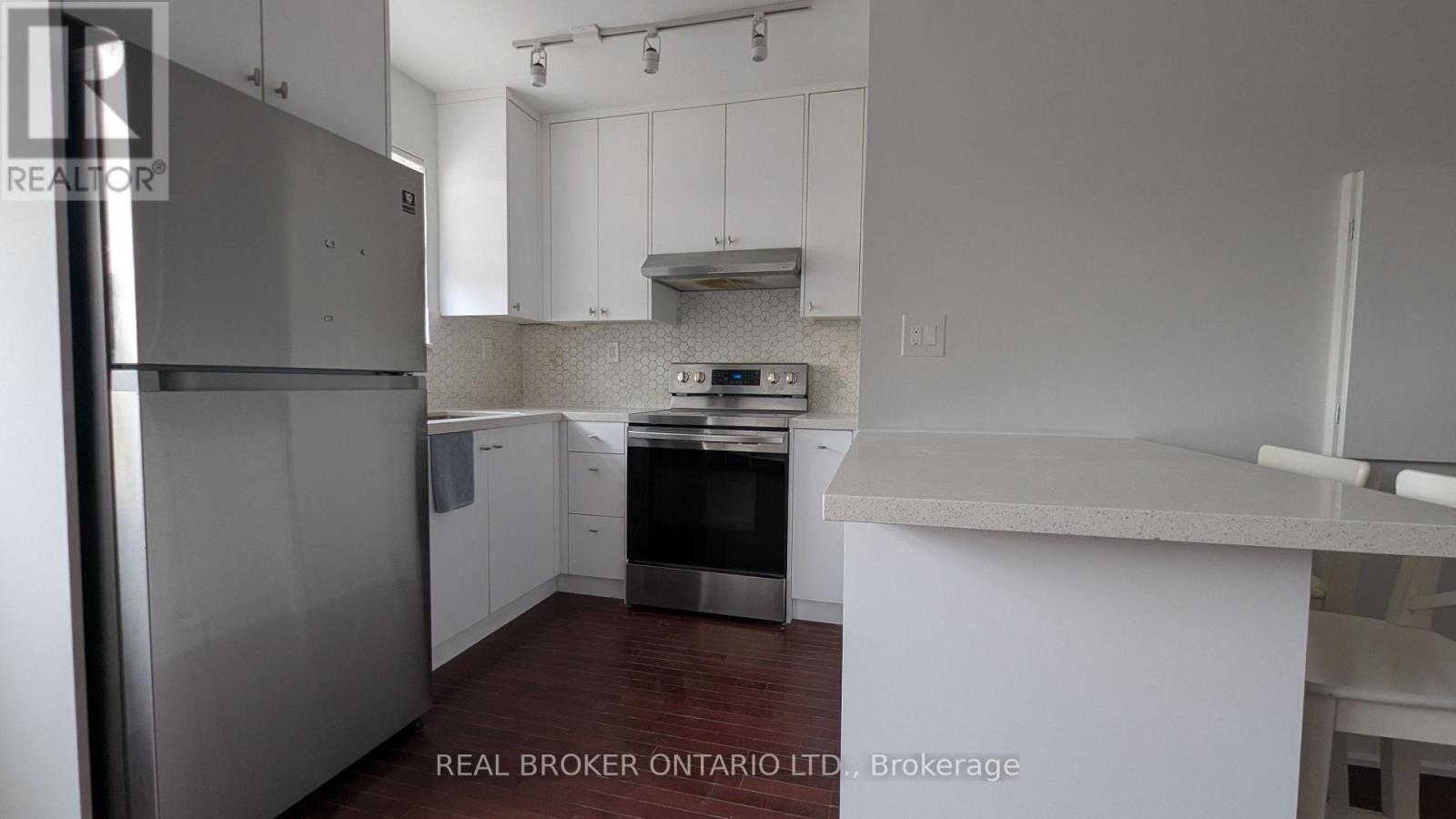 A kitchen with white cabinets and a stainless steel refrigerator.