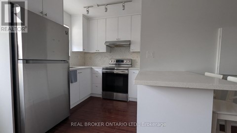 A kitchen with white cabinets and a stainless steel refrigerator.