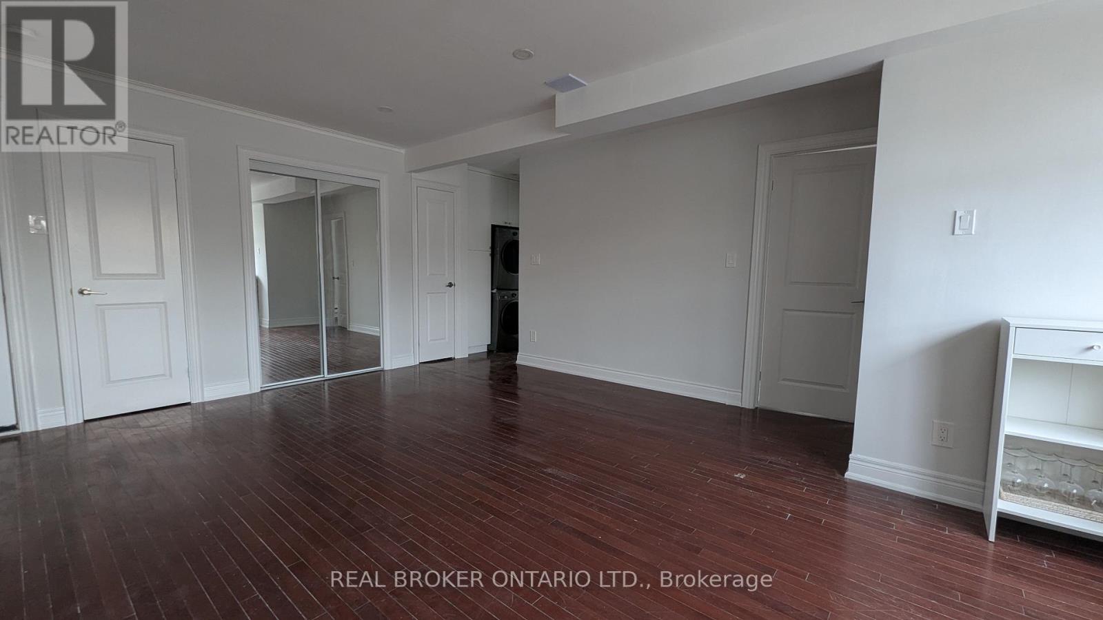 A room with wood flooring and white walls, with a white cabinet on the right.