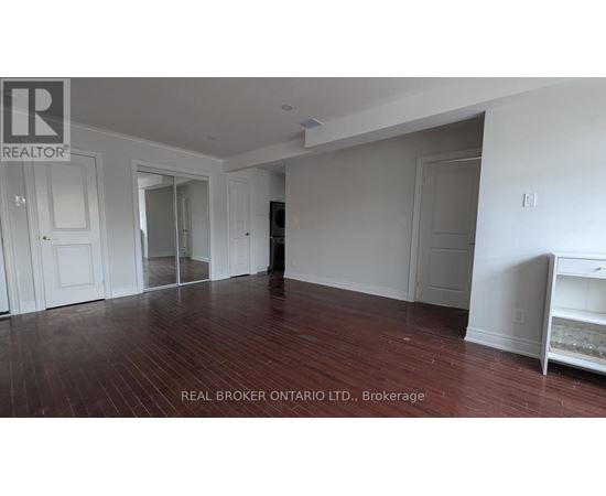 A room with wood flooring and white walls, with a white cabinet on the right.