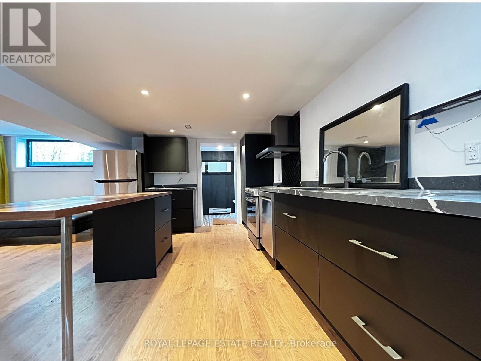 A modern kitchen with wooden floors and black cabinets.