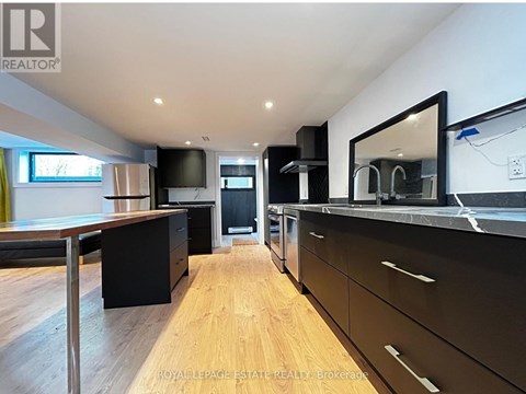 A modern kitchen with wooden floors and black cabinets.
