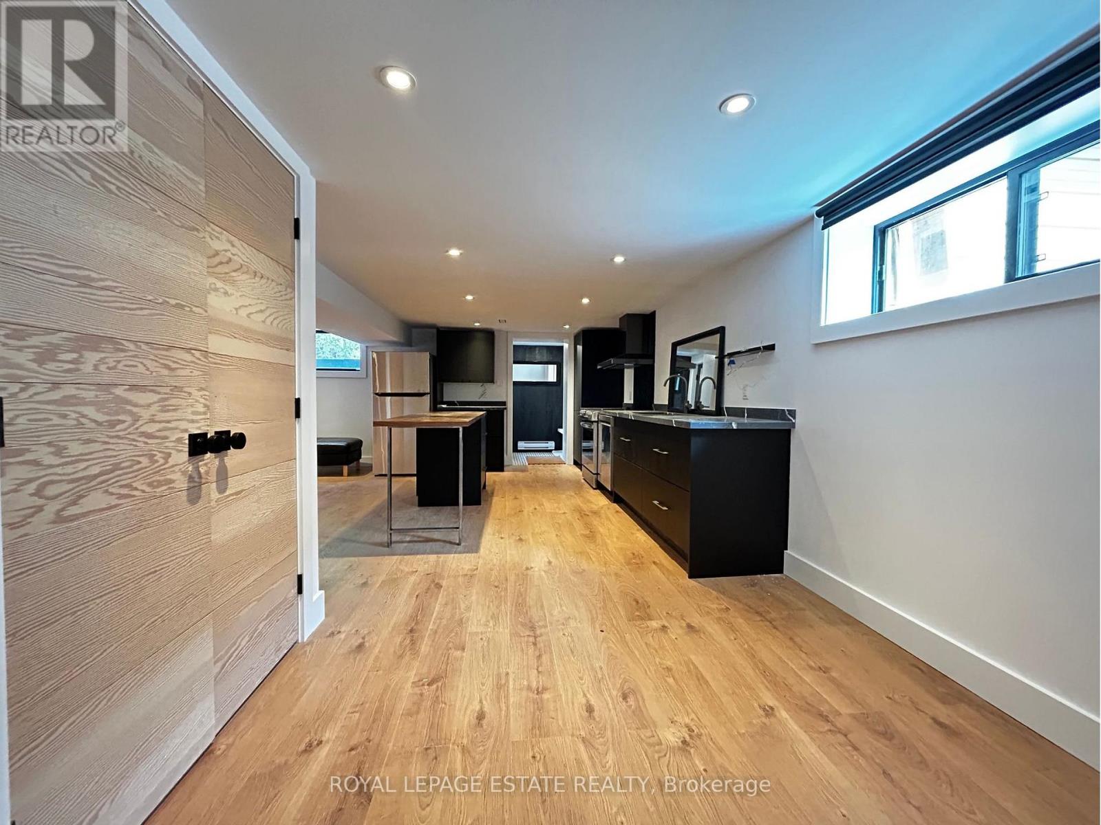 A spacious kitchen and living room with wooden floors and modern appliances.