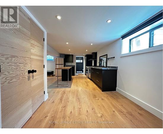 A spacious kitchen and living room with wooden floors and modern appliances.