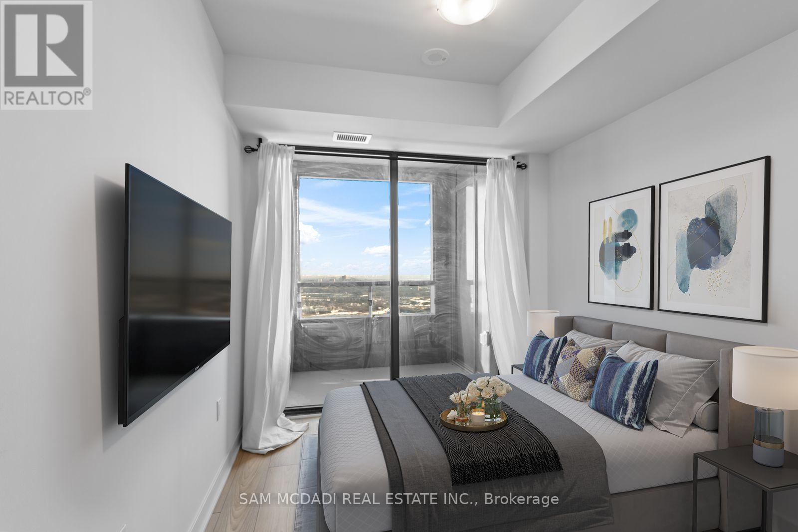 A bedroom with a large bed and a flat screen TV mounted on the wall.