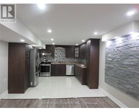 A modern kitchen with dark wood cabinets and a stone wall backsplash.