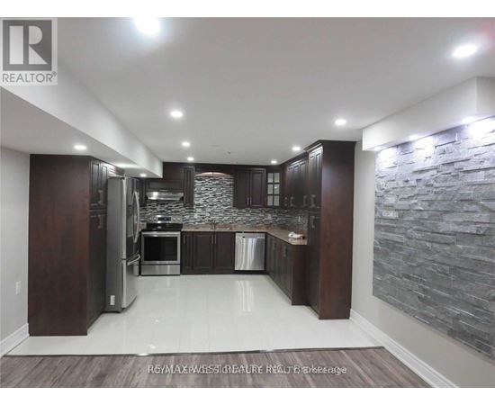 A modern kitchen with dark wood cabinets and a stone wall backsplash.