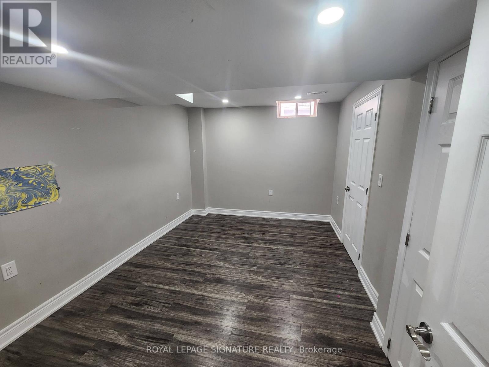 A spacious room with wood flooring and white walls.