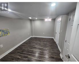 A spacious room with wood flooring and white walls.