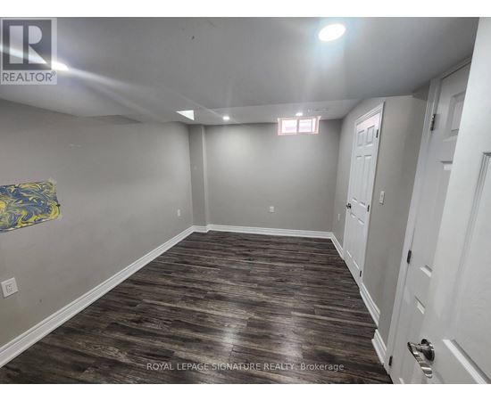 A spacious room with wood flooring and white walls.