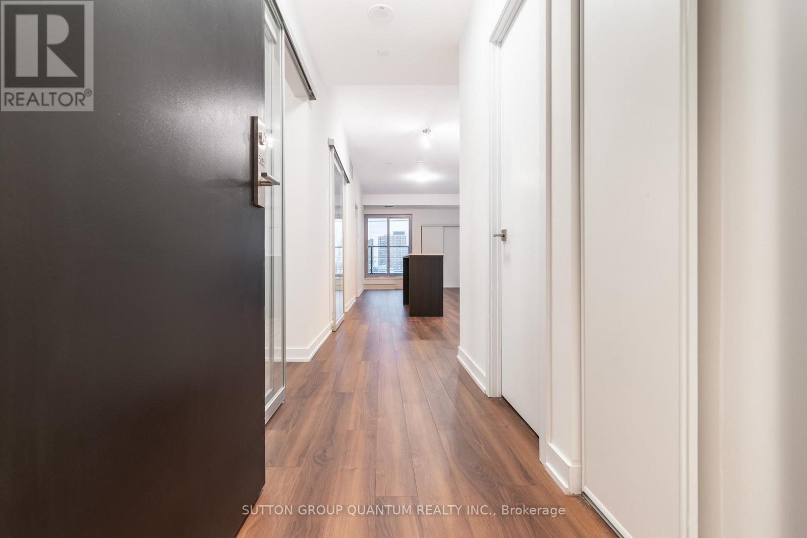 A hallway with a black door on the left and white walls on the right.
