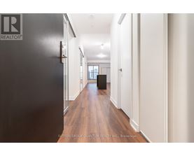 A hallway with a black door on the left and white walls on the right.