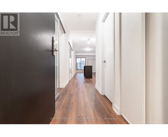 A hallway with a black door on the left and white walls on the right.