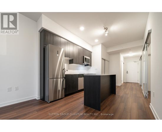 A modern kitchen with a refrigerator, microwave, and stove top oven.