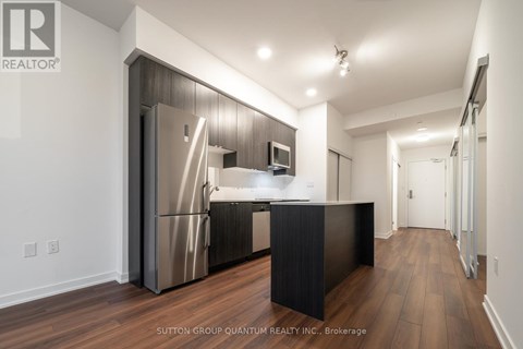 A modern kitchen with a refrigerator, microwave, and stove top oven.