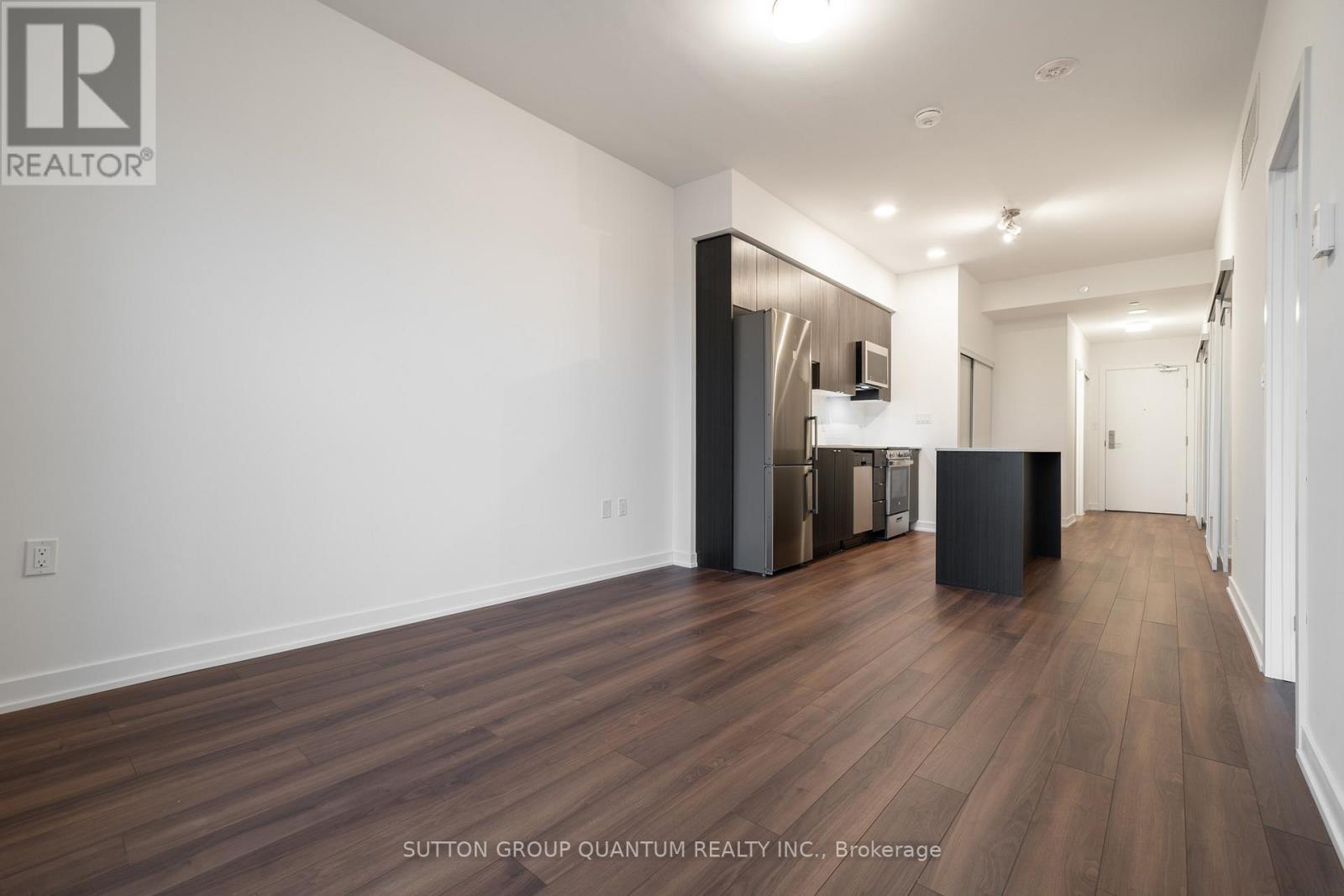 A spacious room with wooden flooring and white walls.