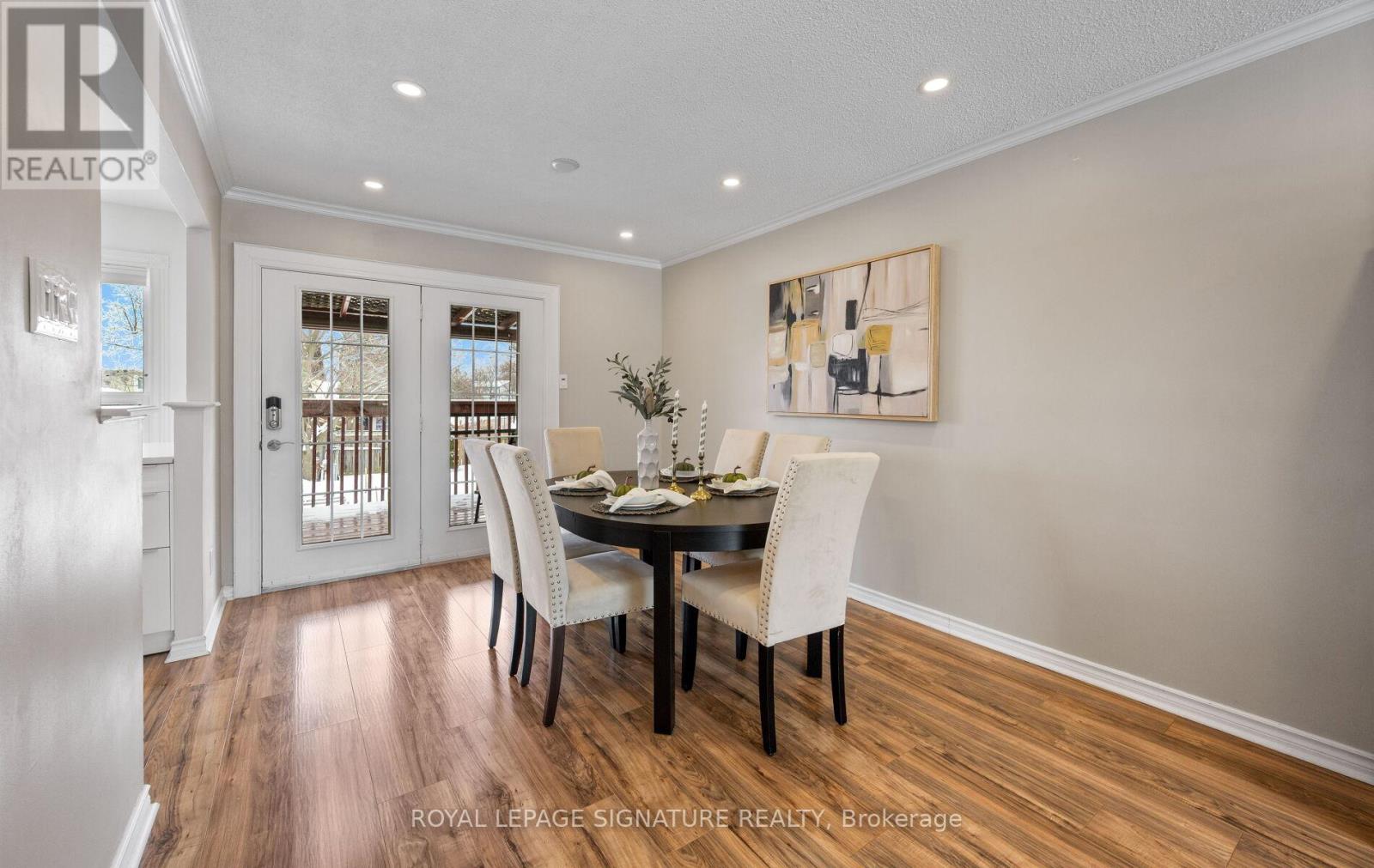 A dining room with a table set for two and a painting on the wall.