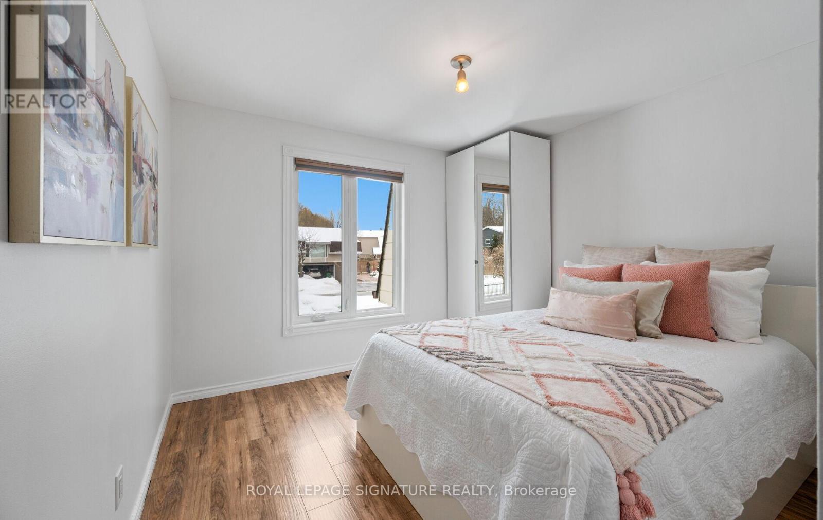 A bedroom with a large bed and a window overlooking a snowy landscape.
