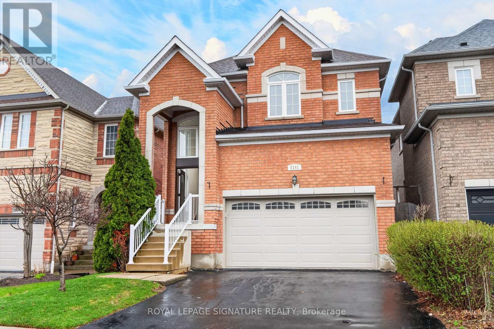 A large brick house with a white garage door and a driveway.