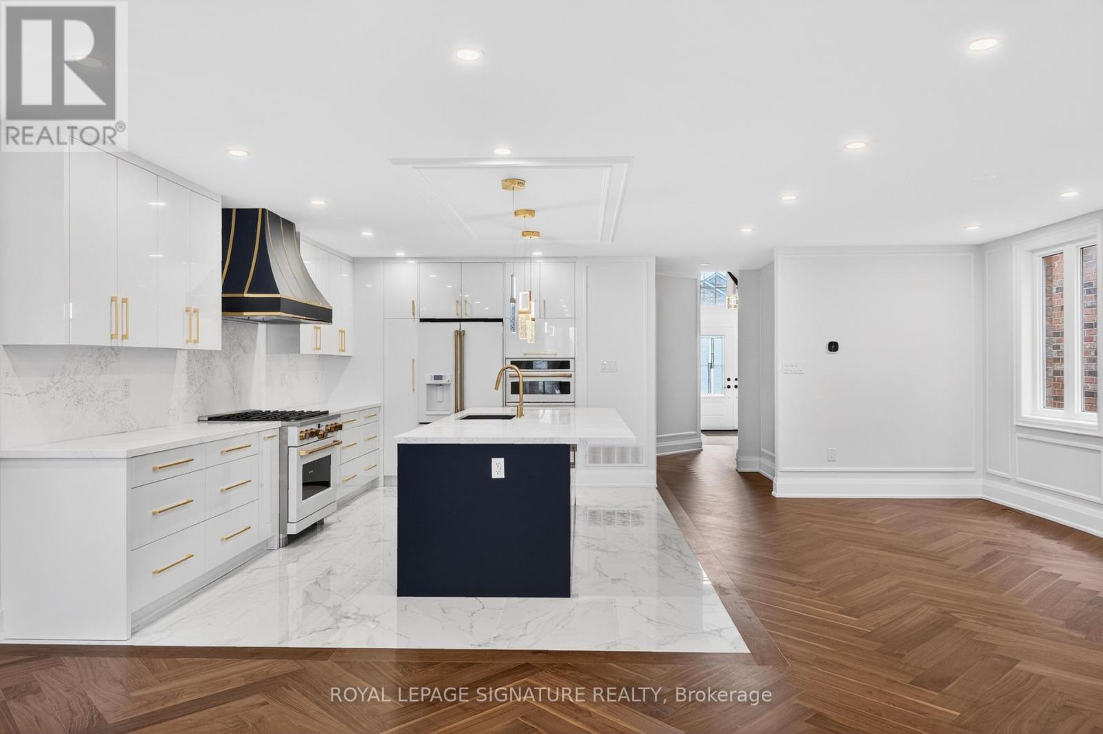 A modern kitchen with white cabinets and a marble island.