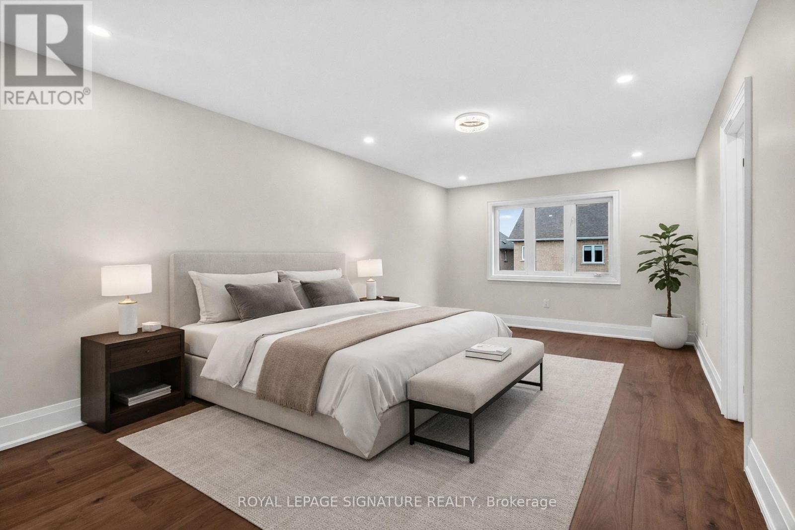 A bedroom with a large bed and a plant in a white pot.