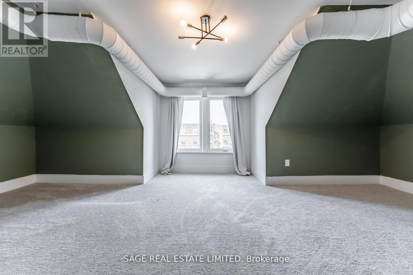 A spacious room with a large window and a chandelier.