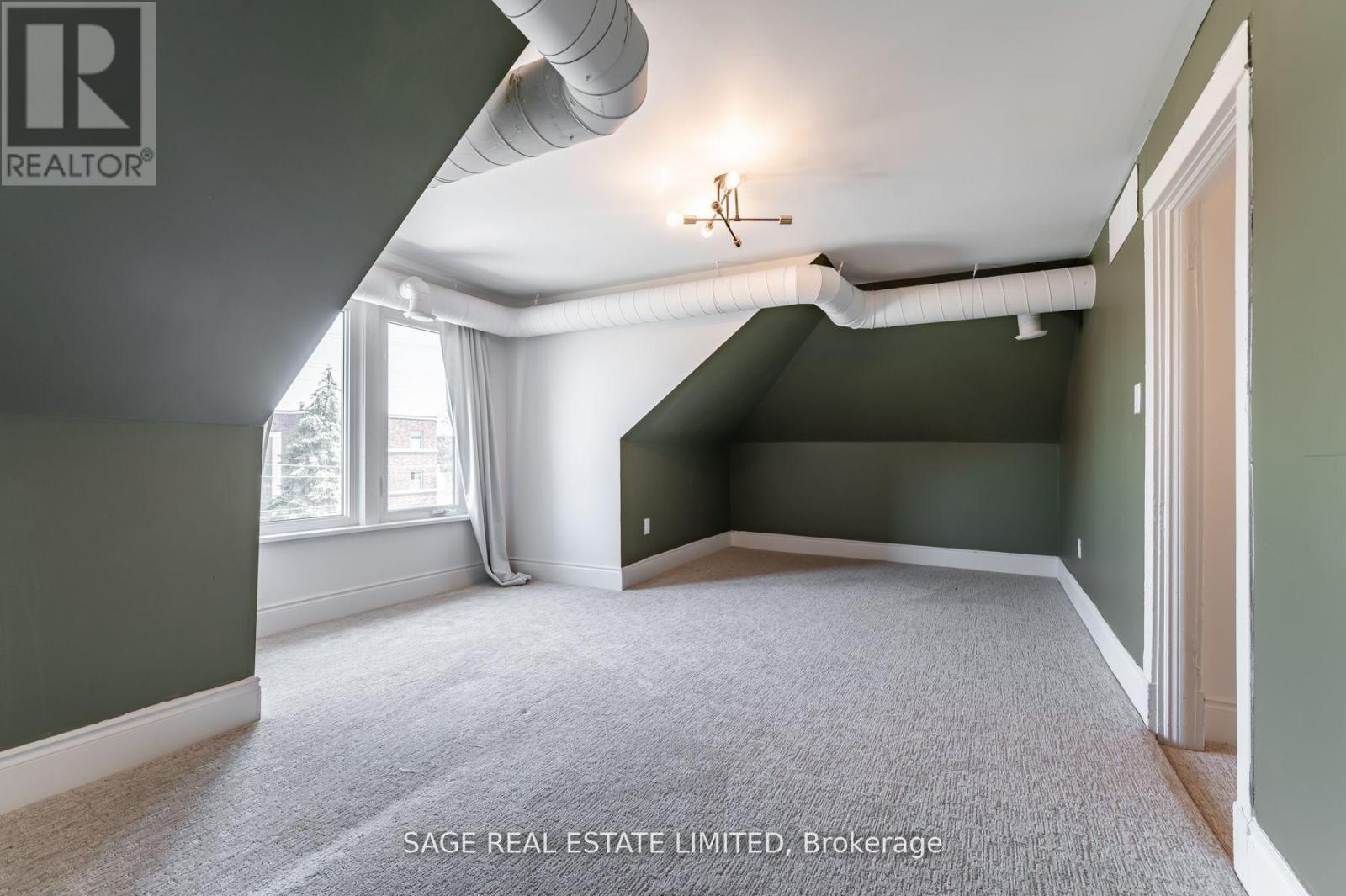 A room with a carpet floor and a window with white curtains.