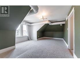 A room with a carpet floor and a window with white curtains.
