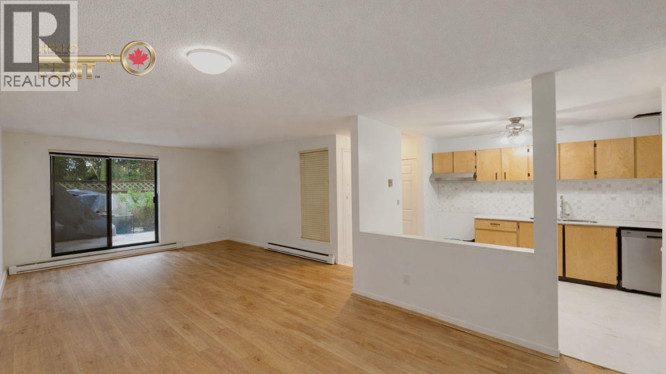 A spacious room with wooden flooring and a sliding glass door leading to a balcony.
