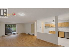 A spacious room with wooden flooring and a sliding glass door leading to a balcony.