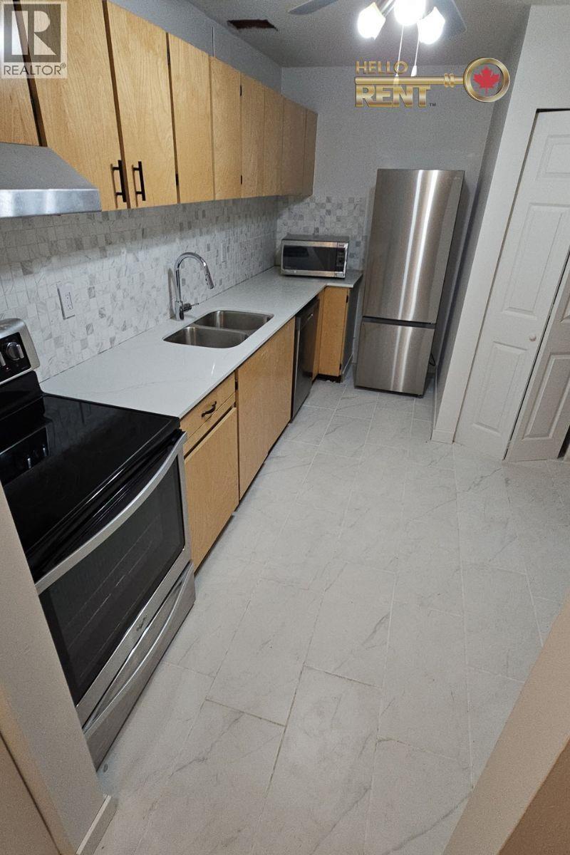 A kitchen with a refrigerator, sink, and stove.