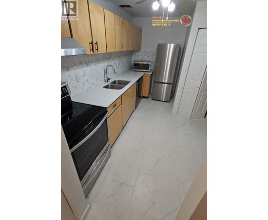 A kitchen with a refrigerator, sink, and stove.