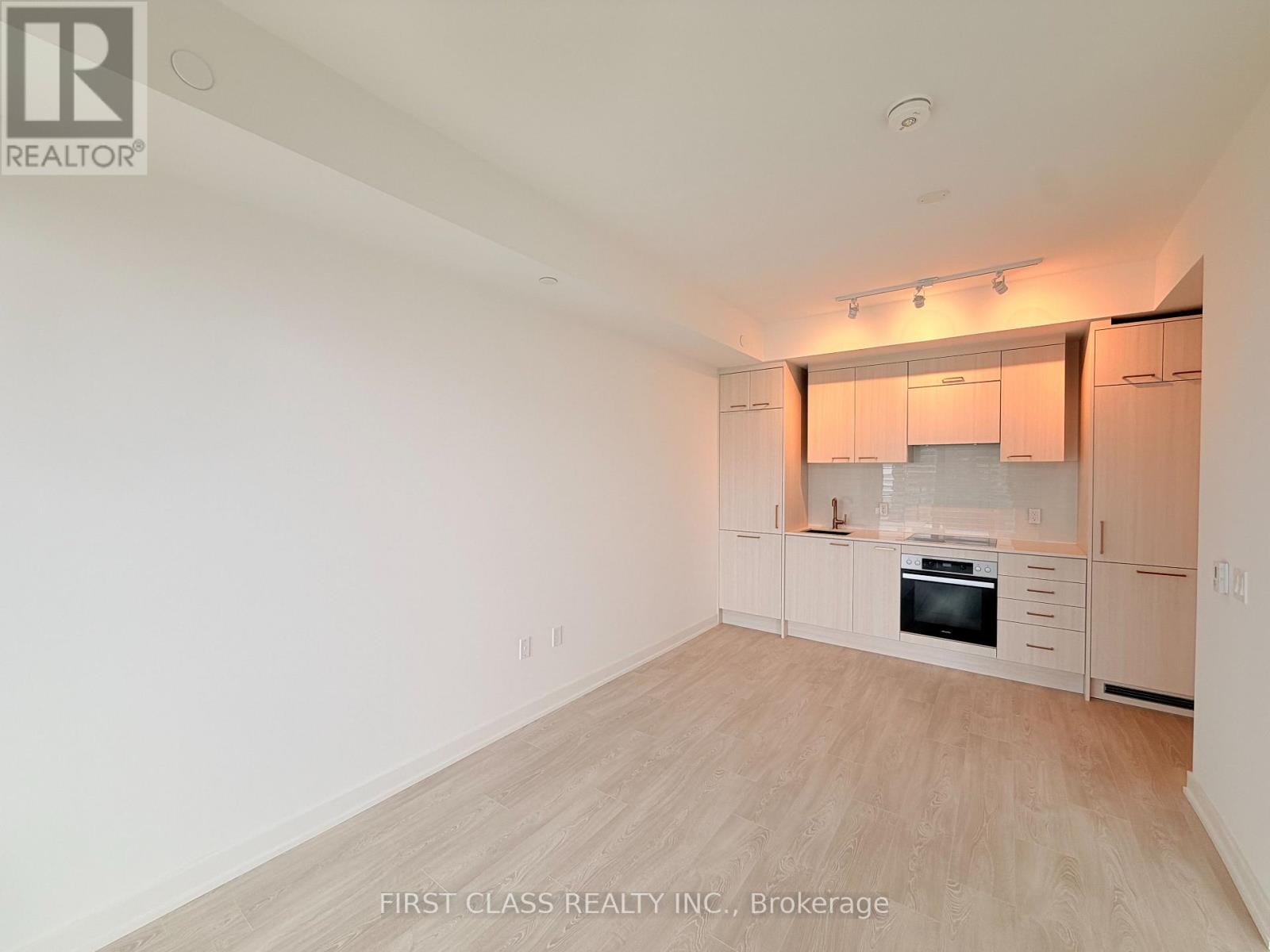 A spacious, empty room with wooden flooring and white walls.