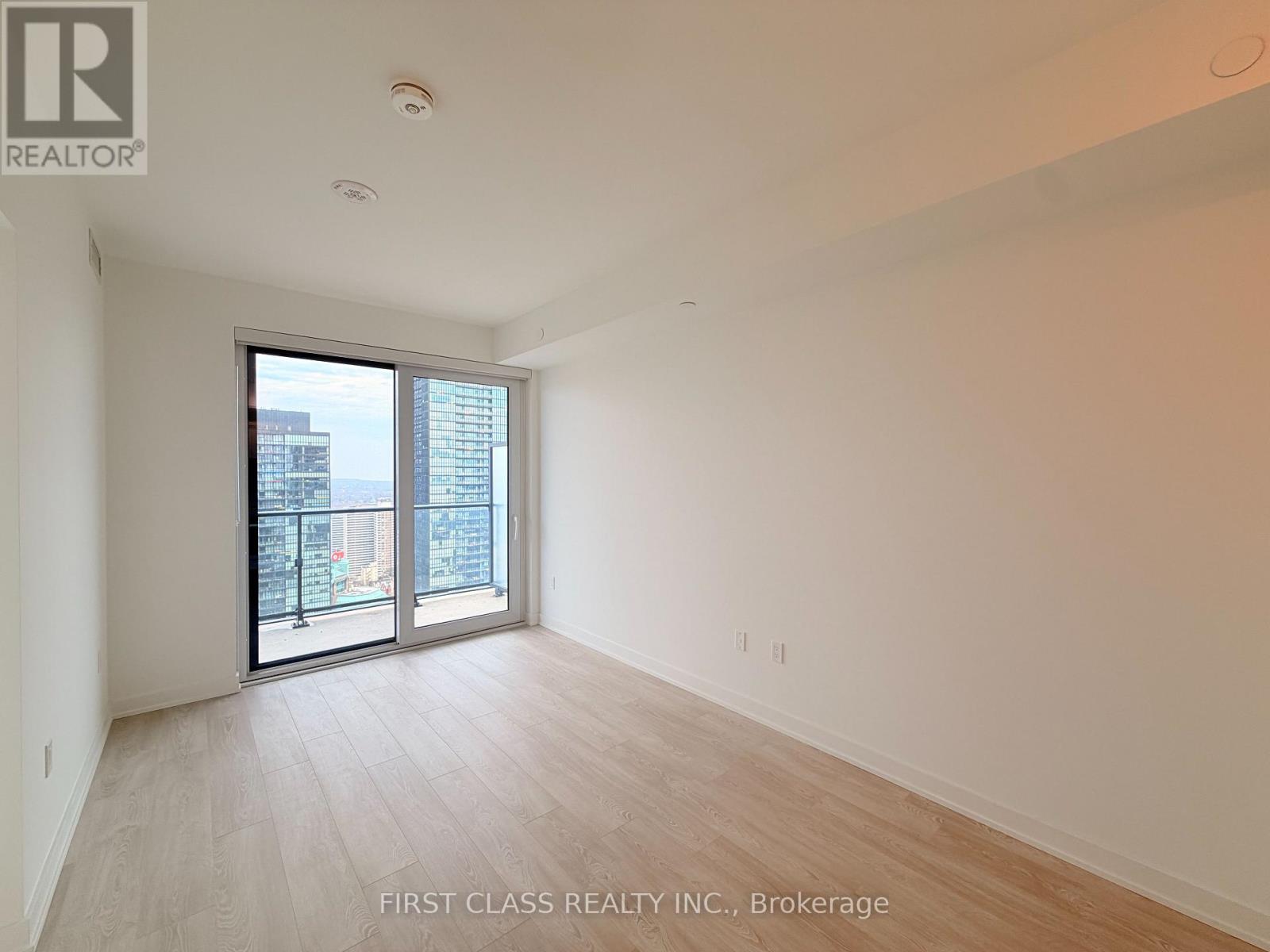 A spacious room with a sliding glass door leading to a balcony.