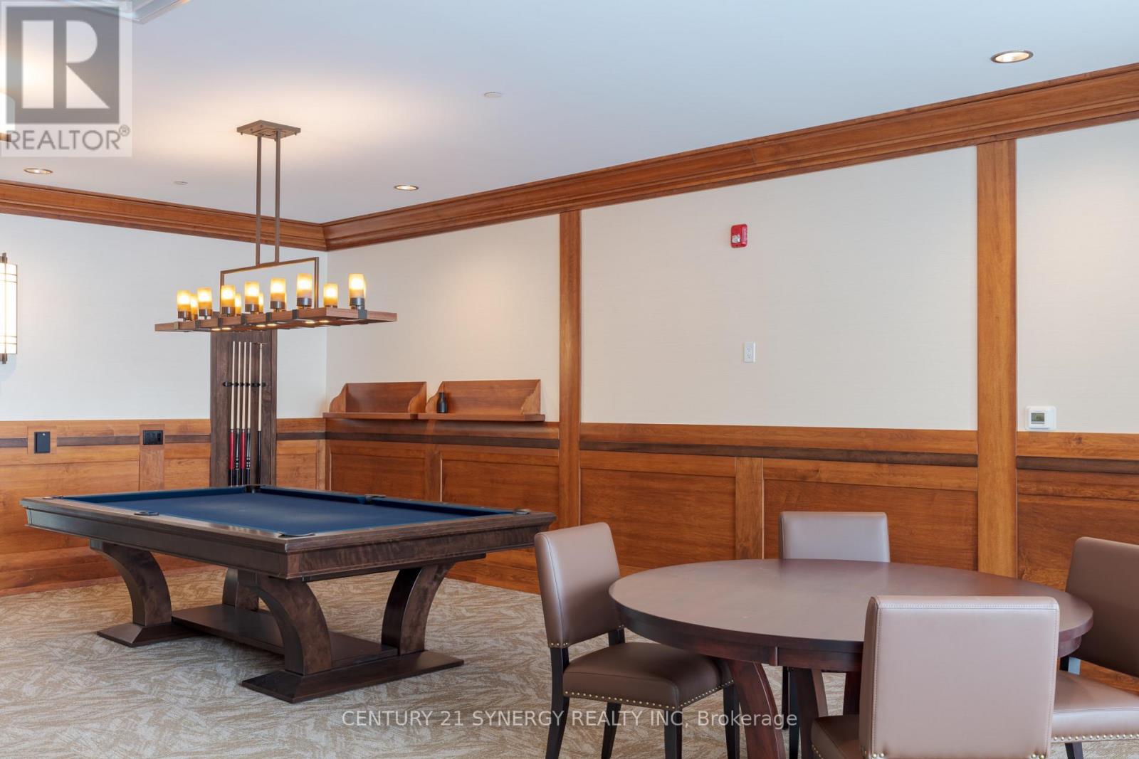 A pool table in a room with a chandelier and a fire extinguisher on the wall.