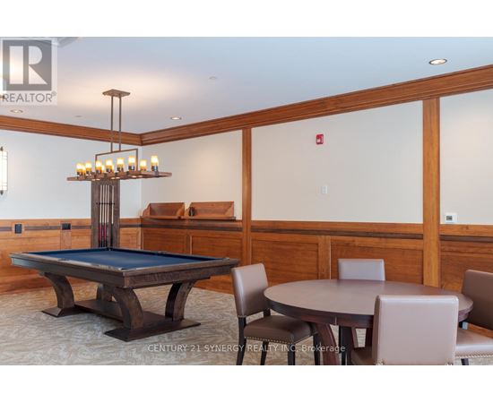 A pool table in a room with a chandelier and a fire extinguisher on the wall.