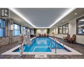 A swimming pool inside a building with a stone wall and a window.