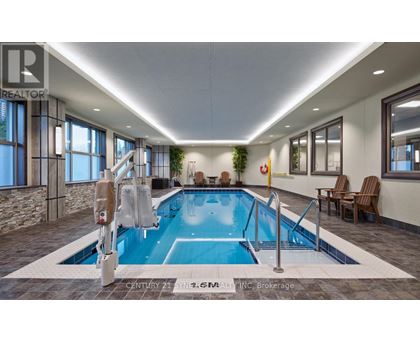 A swimming pool inside a building with a stone wall and a window.