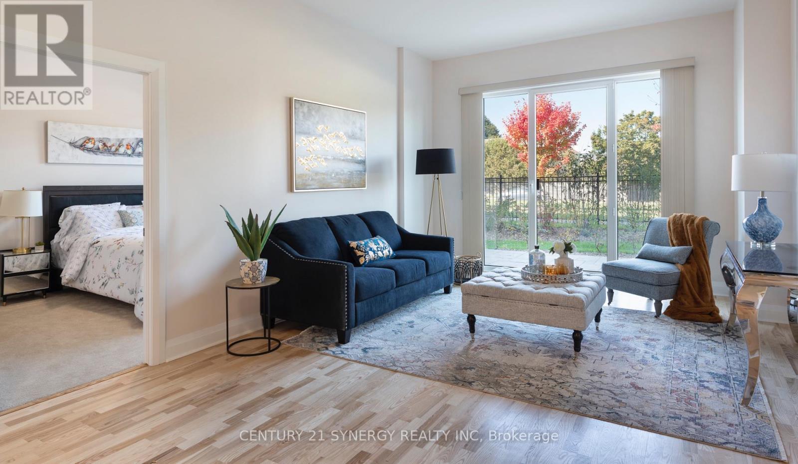A living room with a black couch and a painting on the wall.