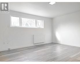 A room with a white wall and a window with a white frame.