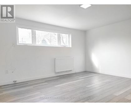 A room with a white wall and a window with a white frame.