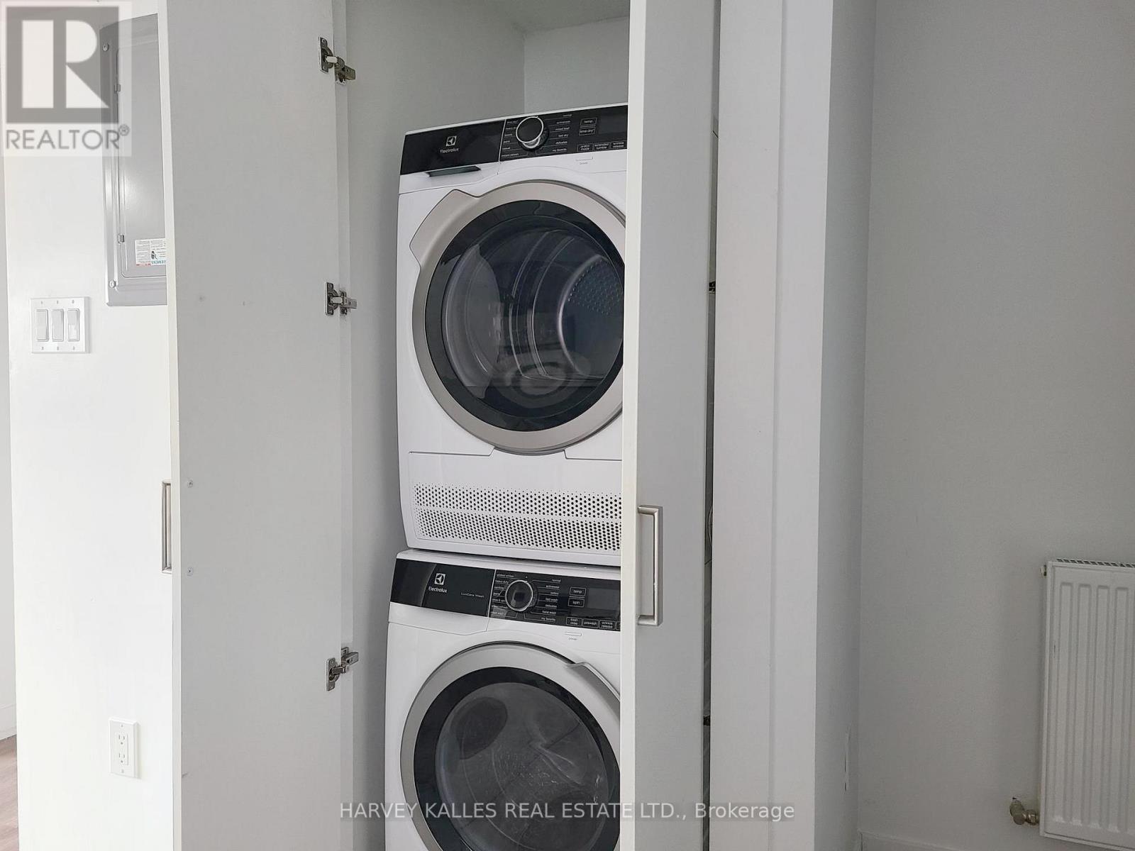 Two washing machines are stacked in a small, white laundry room.