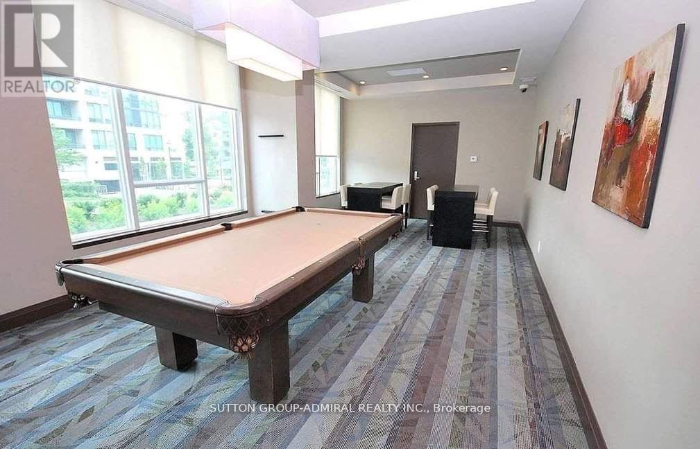 A pool table in a room with a carpeted floor and a window overlooking a building.