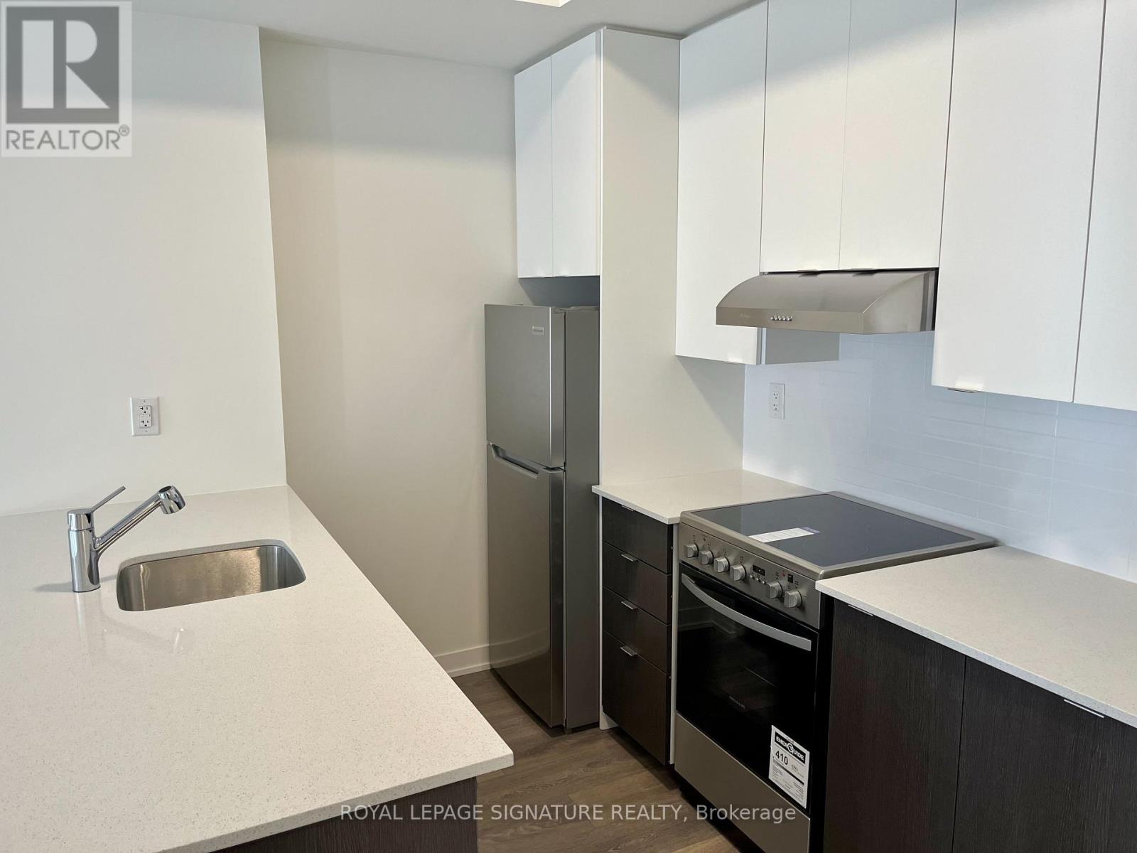 A kitchen with a sink, refrigerator, and stove.