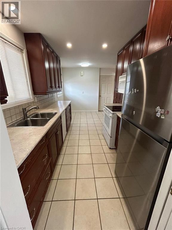 A kitchen with a stainless steel refrigerator and brown cabinets.