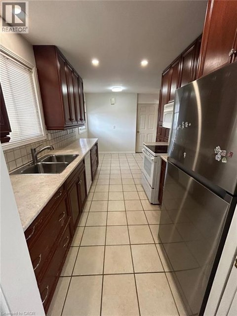 A kitchen with a stainless steel refrigerator and brown cabinets.