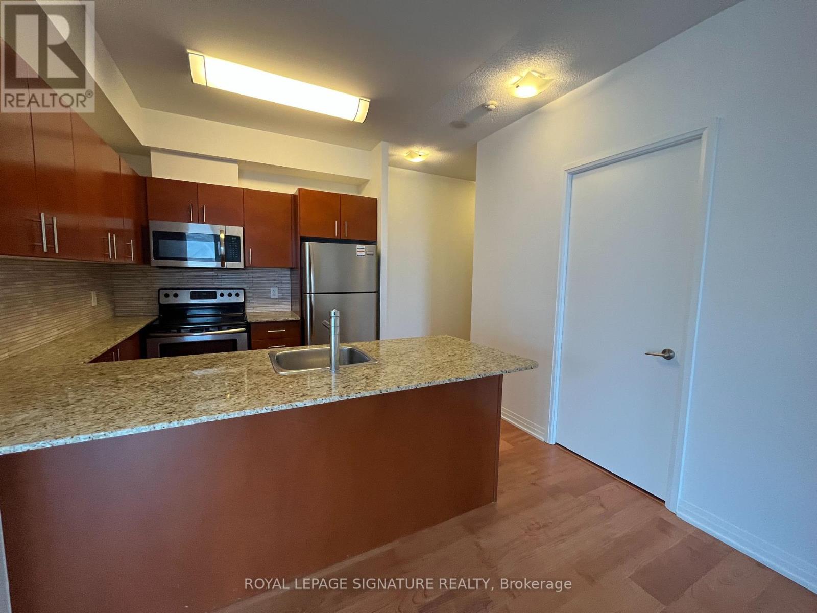 A kitchen with brown cabinets and a granite countertop.
