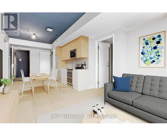 A living room with a grey couch and a painting on the wall.