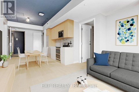 A living room with a grey couch and a painting on the wall.